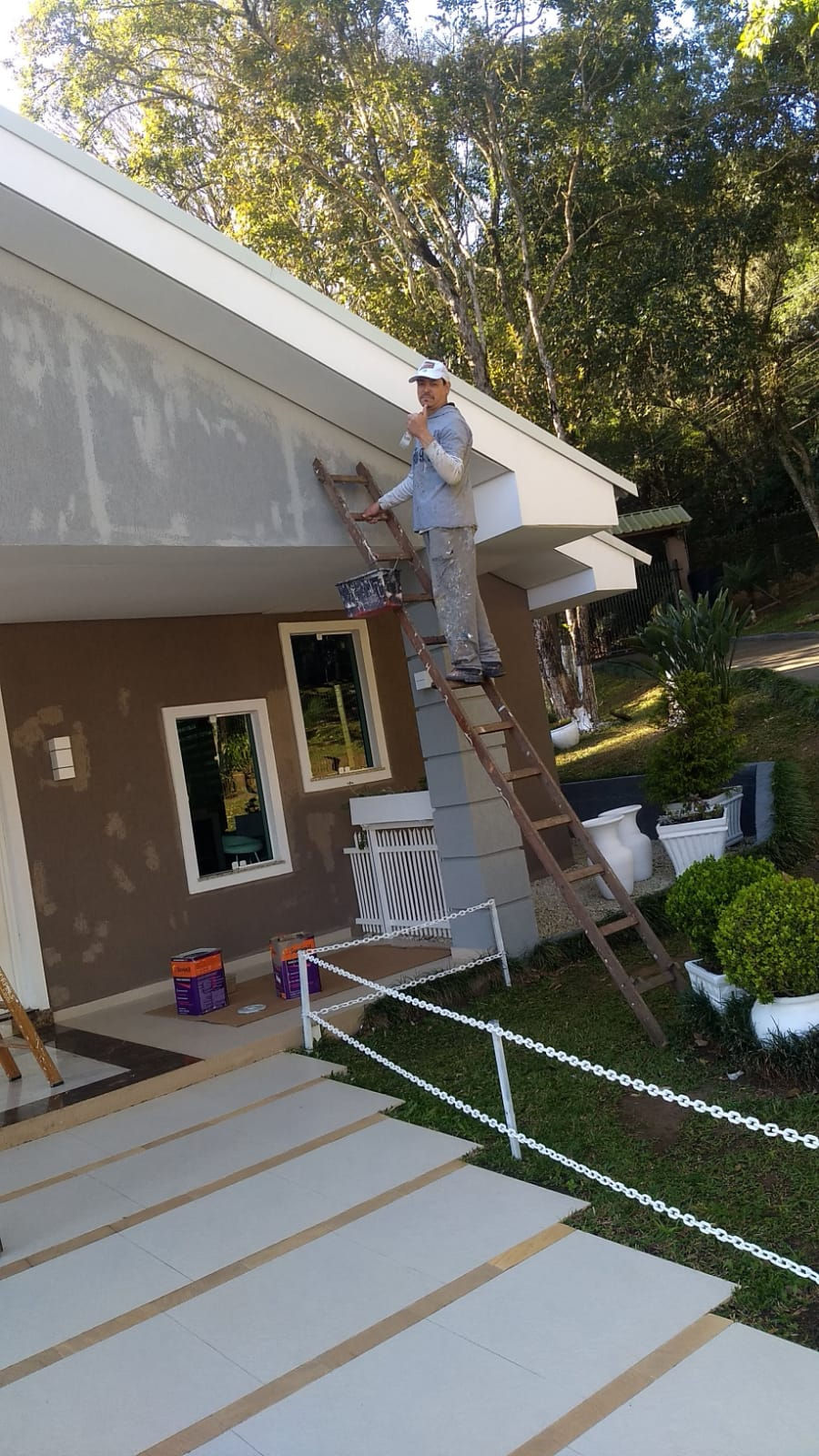 Profissional de pintura trabalhando na fachada de uma casa