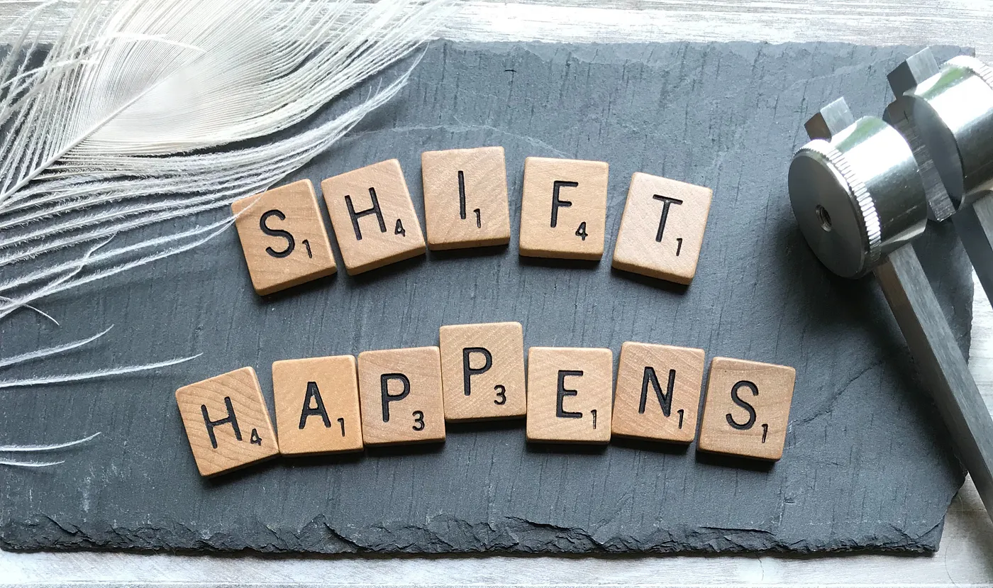 Scrabble tiles that spell out "Shift Happens"