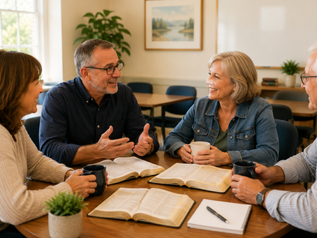 A Sunday School minister encouraging three adult Bible teachers gathered around a table with open Bibles in a bright church classroom