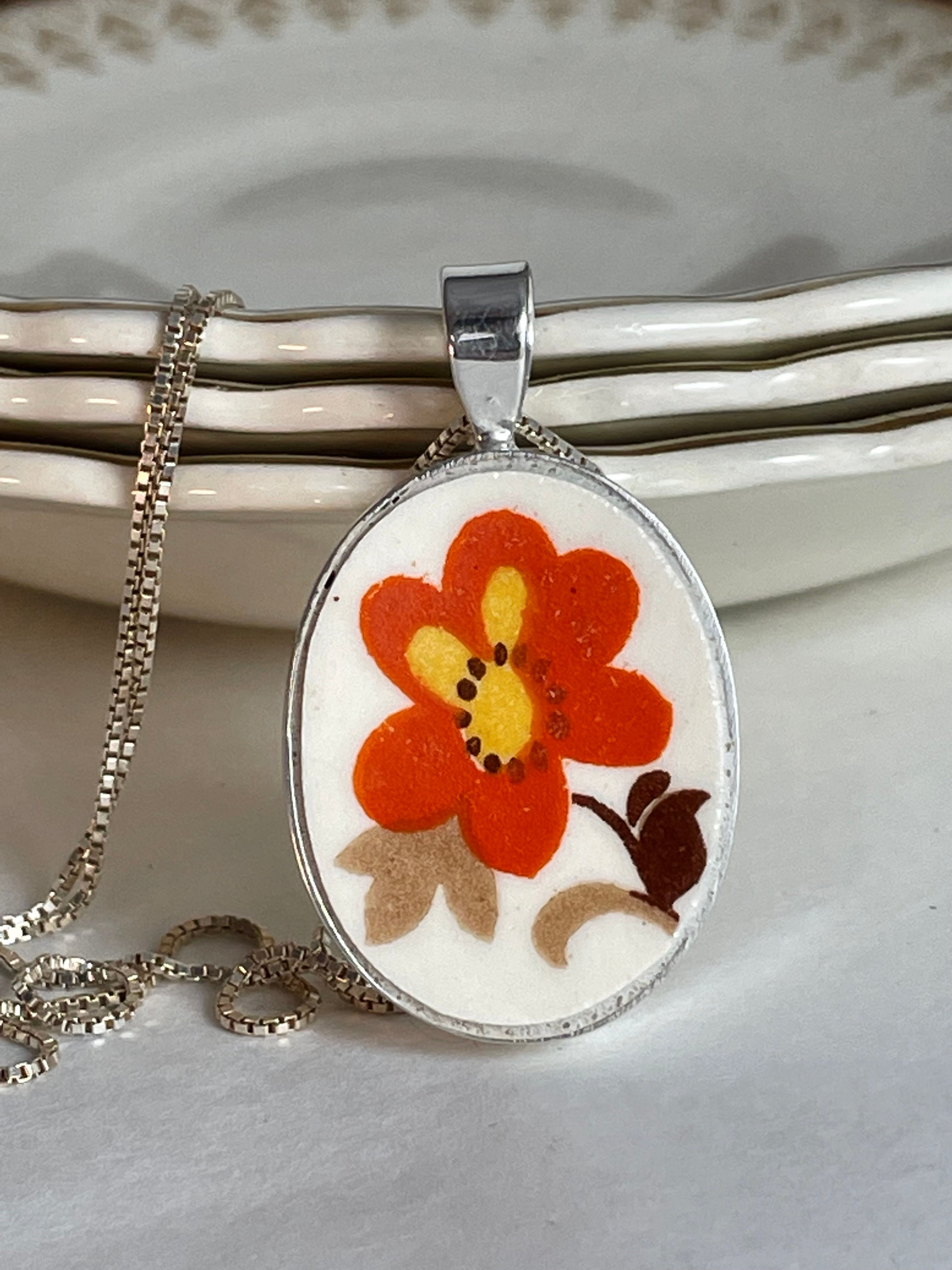 oval pendant with bright orange flower