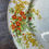 Thumbnail: orange flowers with green leaves in a vintage china plate