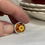 Thumbnail: small round ring with yellow flower on an orange background