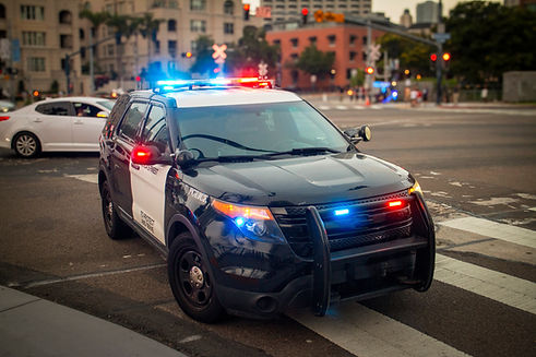 A police car with emergency lights on stopped in an urban environment.jpg