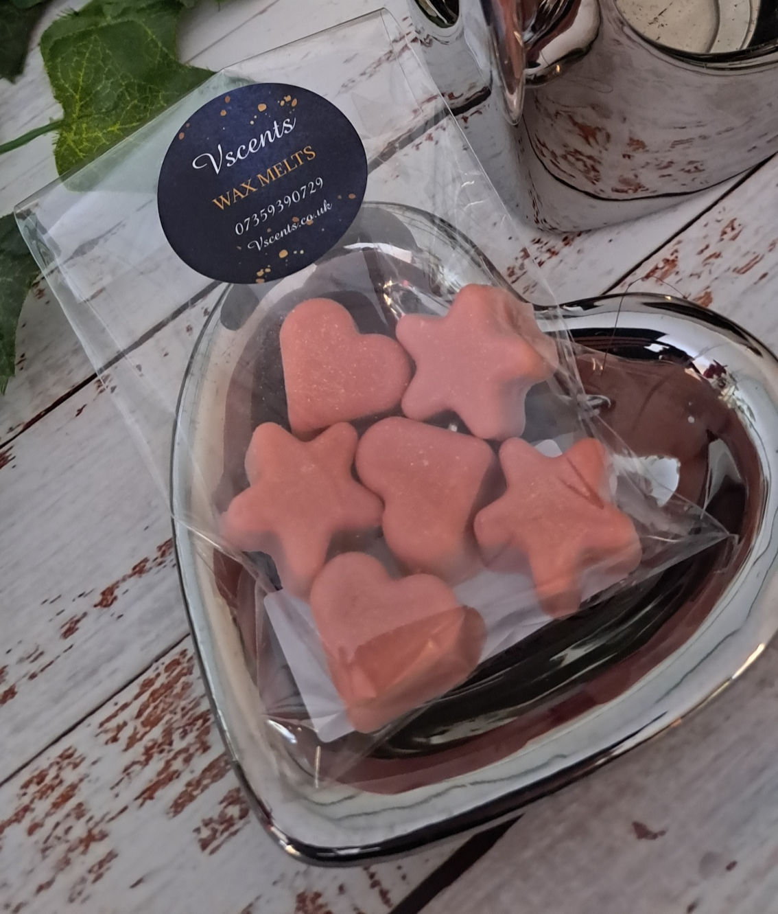 heart shaped silver warming plate that sits on top of a wax burner with a bag of red coloured wax melts.