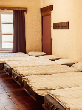 6 lits simples disposés côte à côte dans une chambre avec grande fenêtre