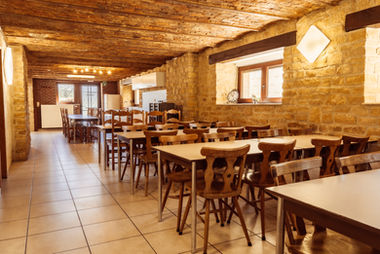 Plusieurs tables et chaises en bois côte à côte dans le prolongement de la cuisine