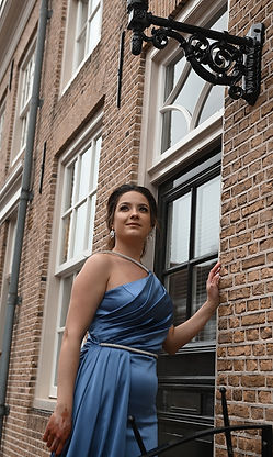 Vrouw in blauwe jurk poseert bij raam, oud gebouw, Naailes den bosch.