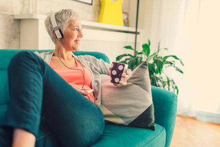 A Woman sitting on a coach listening to StoryStyle™ Audio Learning and exercising her imagination to develop creativity