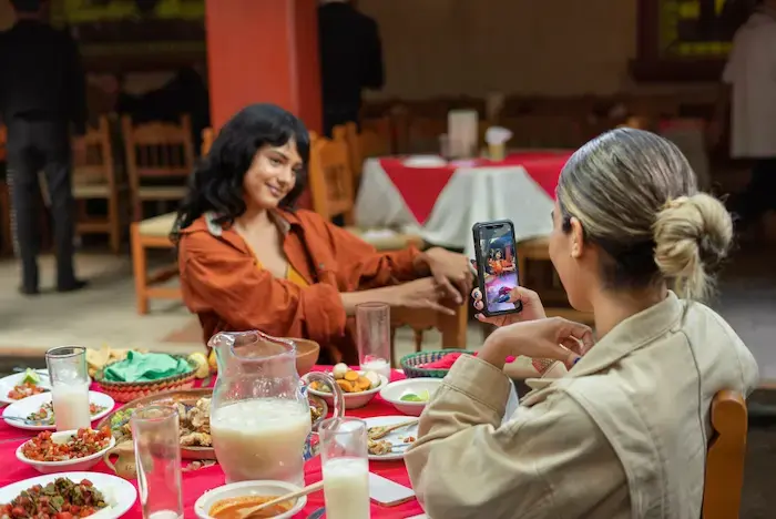 chica tomandole foto a su amiga con su comida en un restaurante en Lince