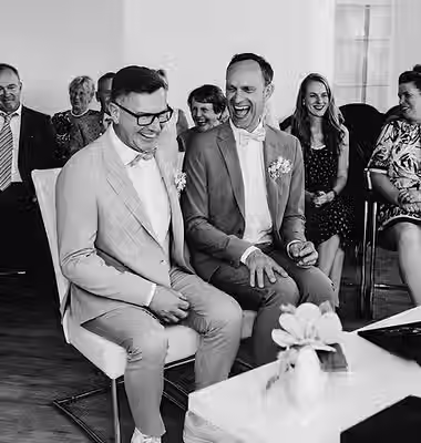 Ein Paar heiratet im Haus des Gastes in Baabe. Sie strahlen vor Freude. Im Hintergrund sind weitere wichtige Personen.