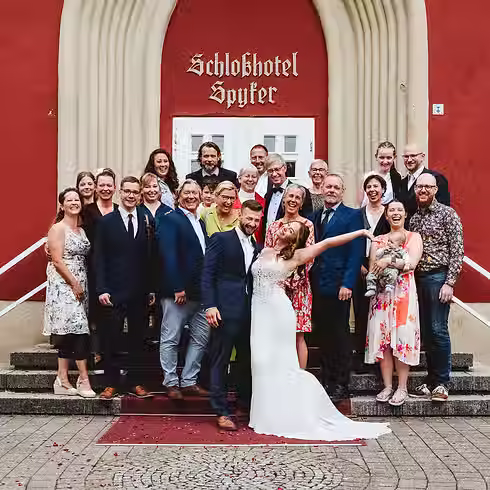 Eine Hochzeitsgesellschaft posiert für ein Gruppenbild am Schlosshotel Spyker. Sie schauen authentisch in die Kamera.