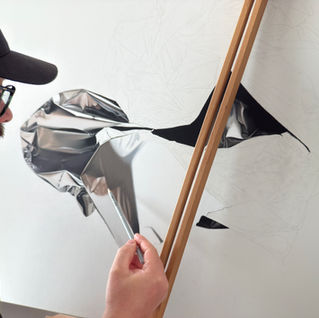 Portuguese artist André Rios in his studio, drawing a hyperrealistic artwork using pastel pencils. The image captures his focused expression and the delicate precision of his technique, highlighting the intricate process behind realistic pastel art.