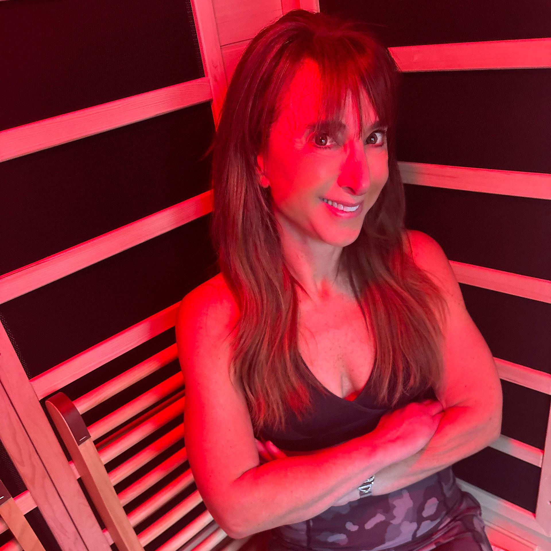 Woman sitting comfortably inside a wooden infrared sauna.