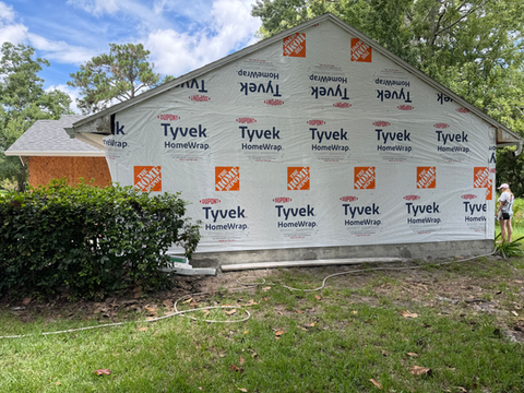 Home wrapped in Tyvek with visible text, construction, and FLOCON Contractors LLC.