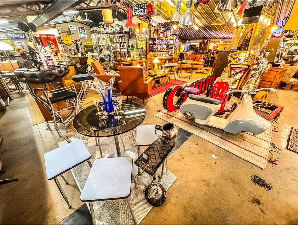 Intérieur d'un magasin vintage avec chaises, table en verre avec vase bleu. Objets rétro colorés, affiches et enseignes murales. Ambiance rétro.