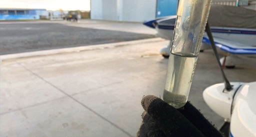 A pilot sampling the fuel from a light aircraft