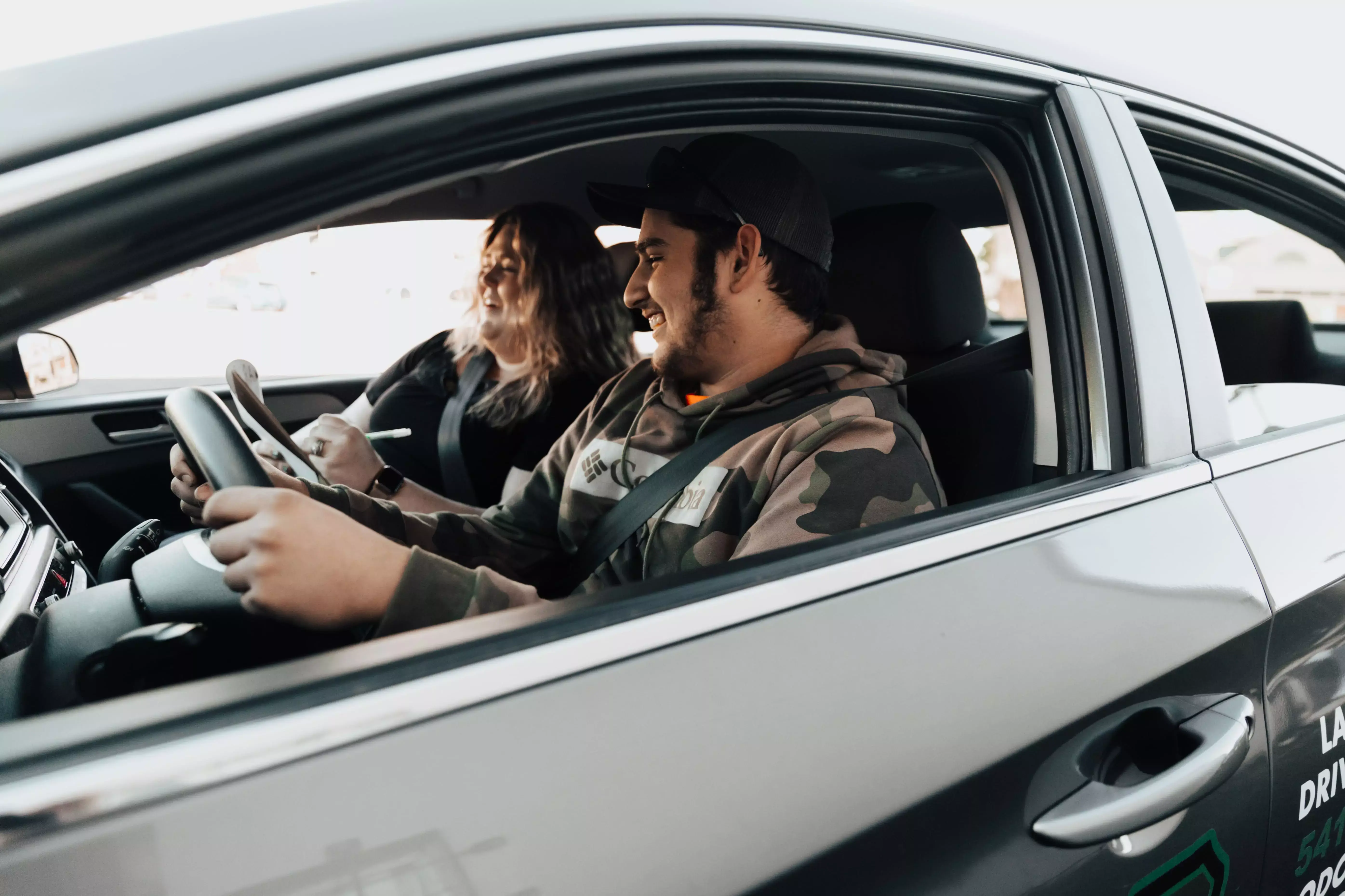 passenger side view of teachers hands filling out a form on a clipboard.