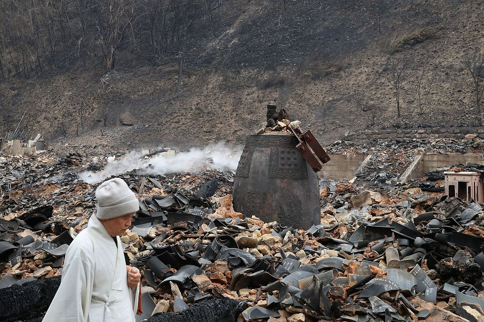 Man walking past the burned remains of a temple in South Korea