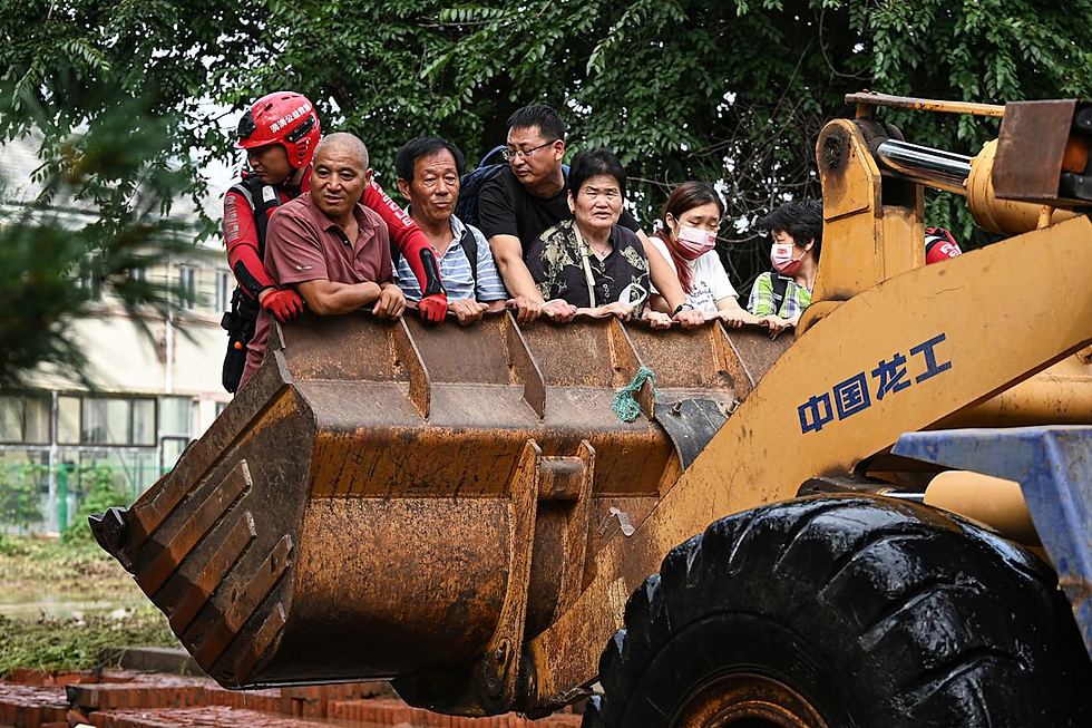 Residents ride on a front loader to cross a flooded street in Taishitun village on Sunday