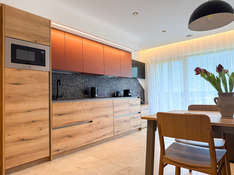 Cucina moderna con mobili in legno, pensili rossi e zona pranzo.