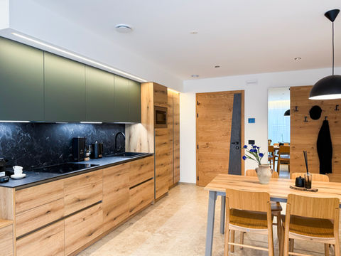Cucina moderna con mobili verdi e tavolo da pranzo in legno