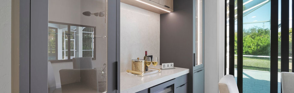 Modern handcrafted bar cabinets designed with glass displays, wood veneer, and built-in wine cooler for a Pine Ridge Naples home.