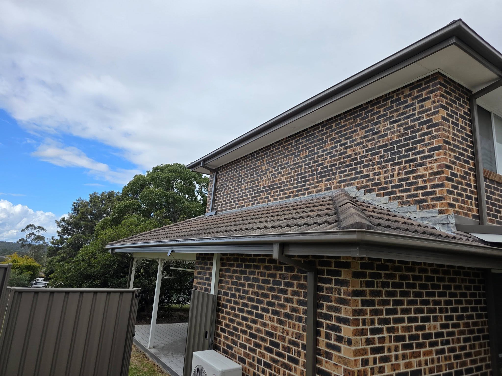 Two-storey brick home with a tiled roof and gutters