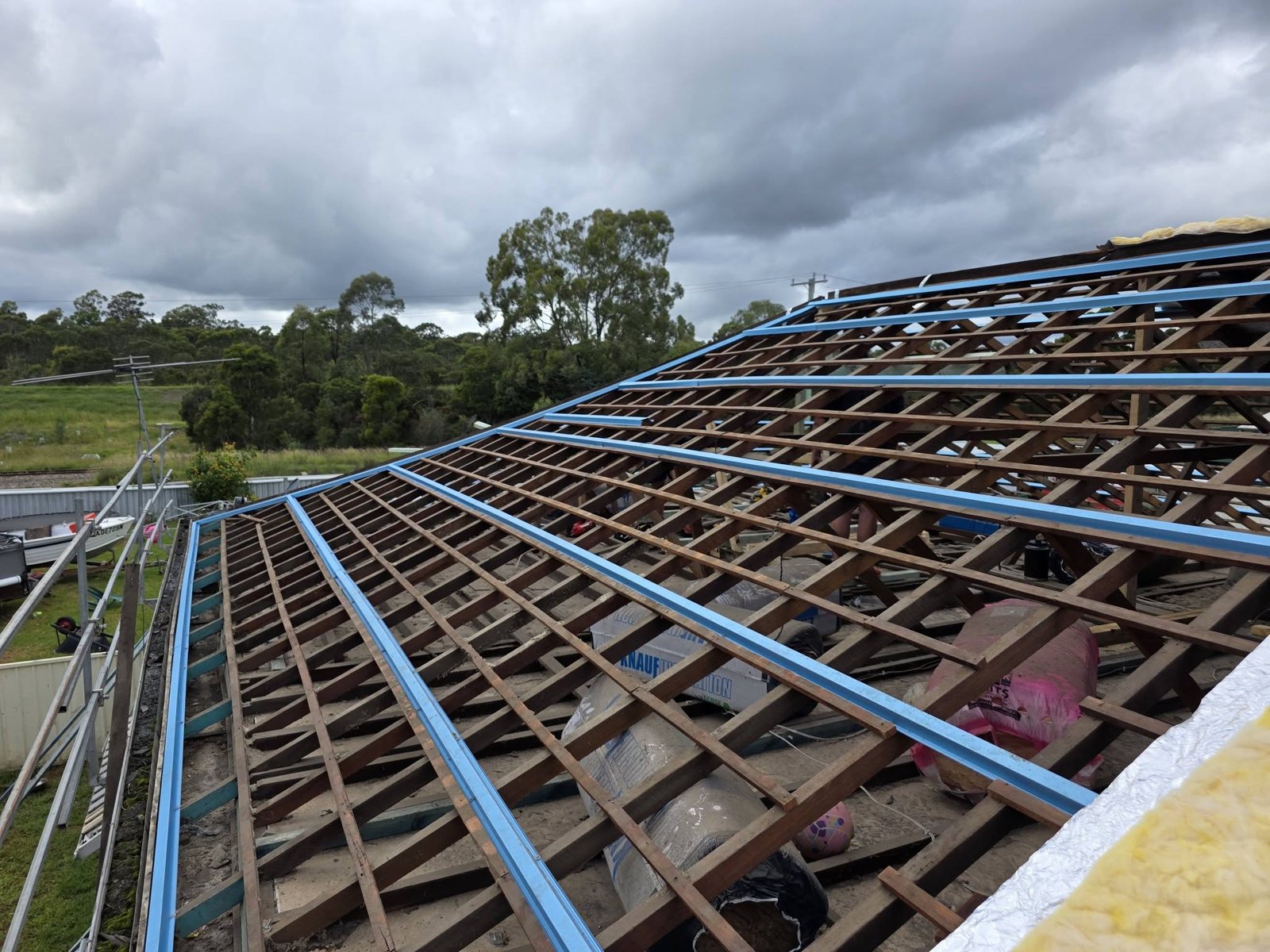 Roof stripped of its tiles with new steel battens going on ready for metal sheets