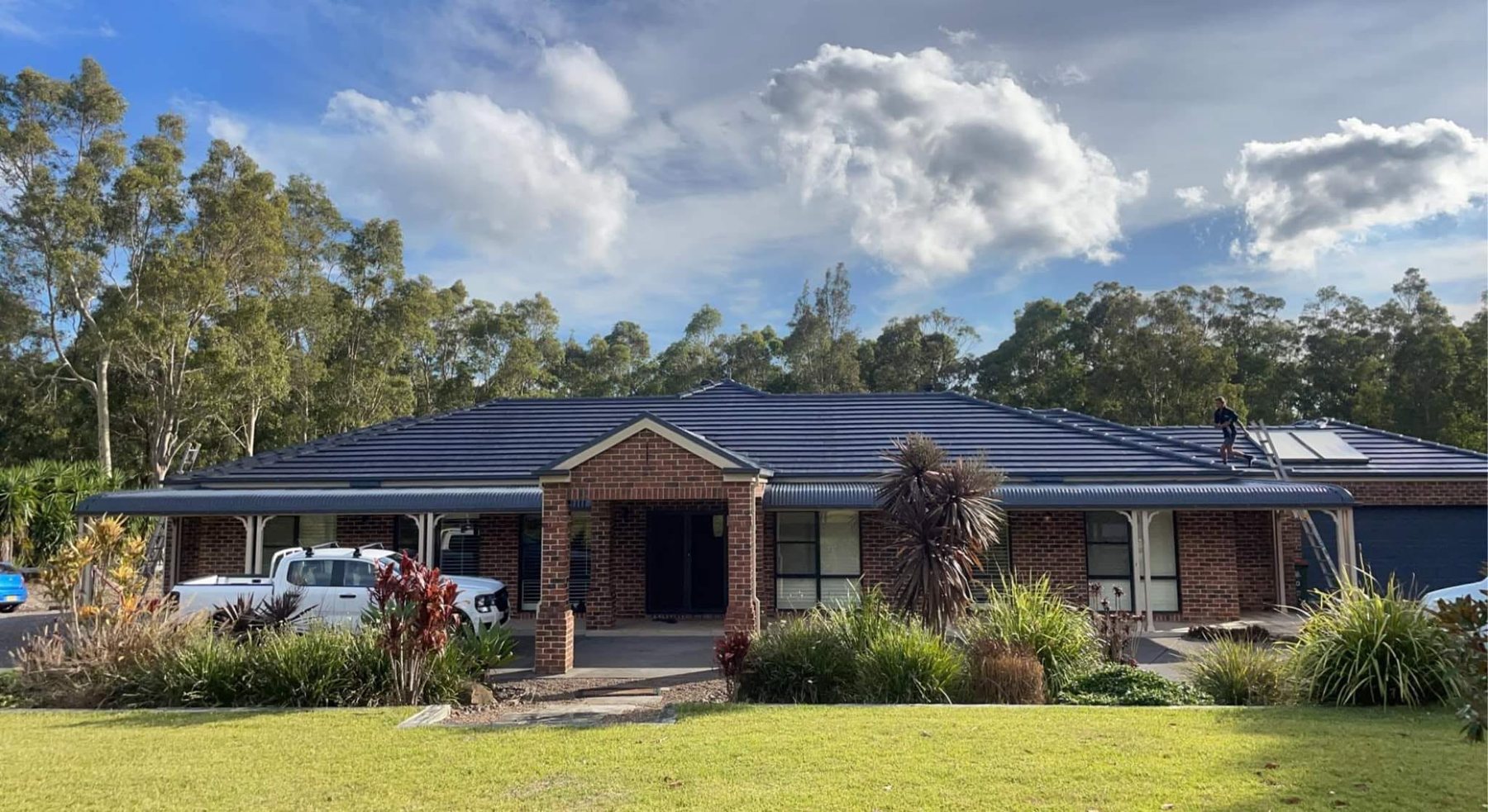 Single-storey brick home with its tiled roof freshly coated in dark blue