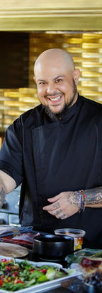Cuban man wearing chef jacket, preparing food, smiling at camera