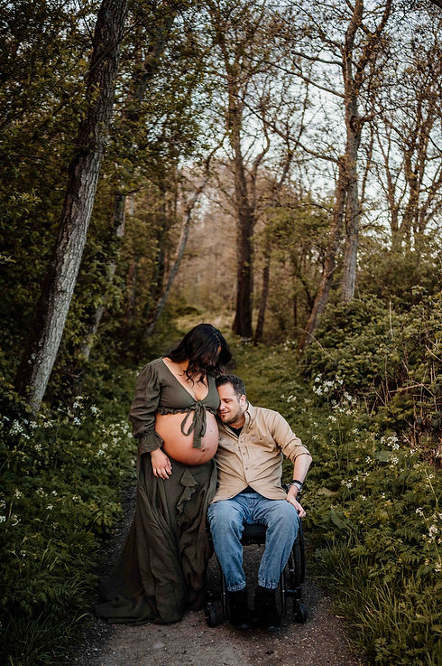 Zwangere vrouw en haar man in rolstoel in bos