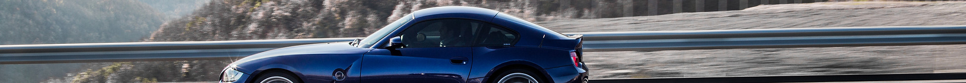 navy-blue-coupe-sedan-driving-highway-accross-mountains.jpg