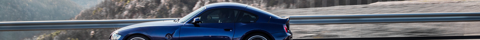 navy-blue-coupe-sedan-driving-highway-accross-mountains.jpg