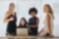 Group of multiracial businesswomen in casuals together at office desk and looking at camer