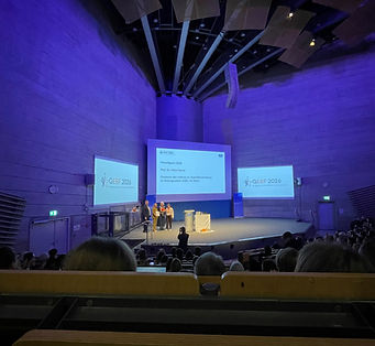 Podium mit Panelteilnehmenden auf einer Bühne