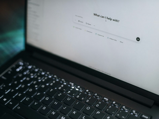 Laptop displaying the ChatGPT home screen with the prompt ‘What can I help with?