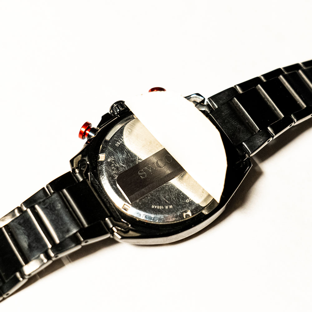 Watch back with something taped to it.