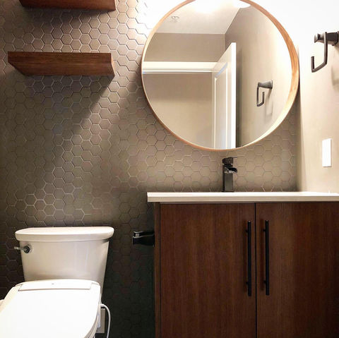 Moody bathroom with hex backsplash, framed mirror and bathroom vanity cabinet.