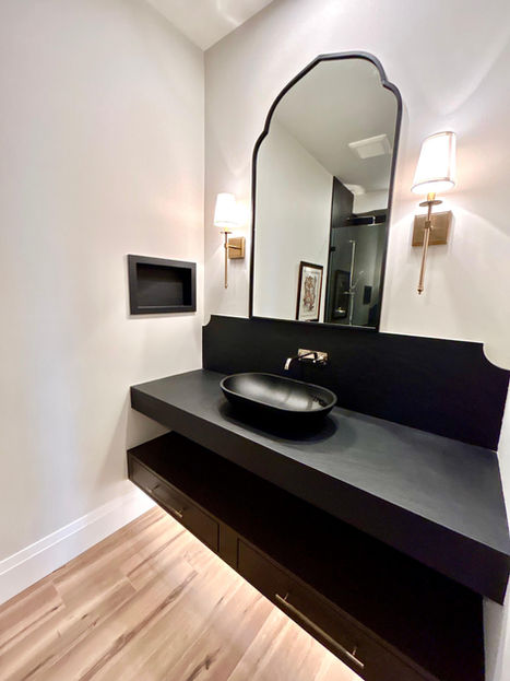 Powder room black floating counter, mirror and wall sconces.