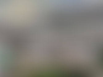 Vista aérea panorâmica de um bairro residencial em Teófilo Otoni, Minas Gerais, mostrando casas construídas em encostas e montanhas ao fundo sob céu nublado.