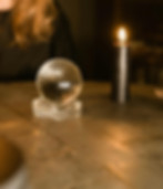 Woman looking down over a crystal ball with a tall candle sitting each side of it
