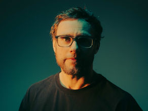 Portrait of a man with glasses in dramatic teal and orange studio lighting, looking directly at the camera