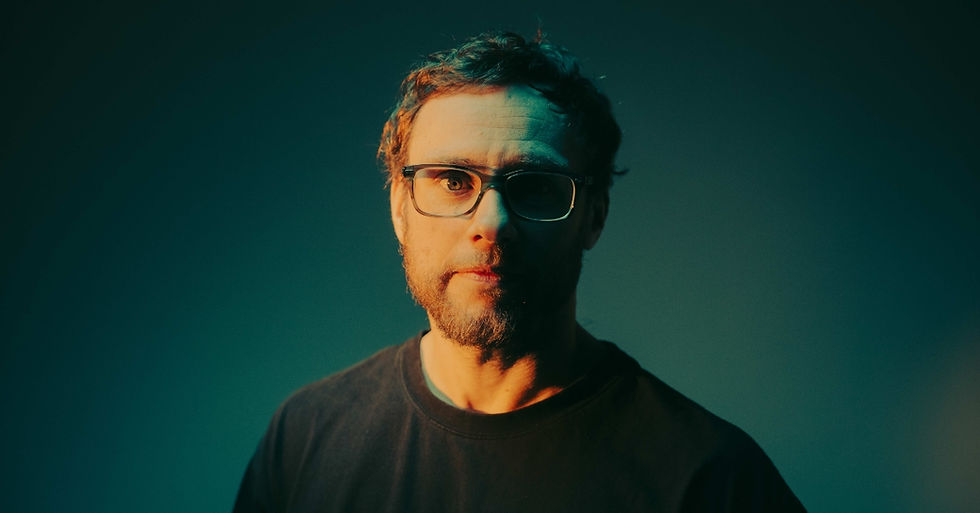 Portrait of a man with glasses in dramatic teal and orange studio lighting, looking directly at the camera