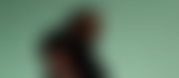 Blurry low-angle view of a man in a black shirt against a pale green sky, looking away with a contemplative mood.