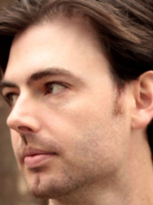 Close-up of a thoughtful young man looking left against a blurred wooden background.