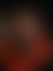 Man in orange hoodie against dark background, face partially blurred, conveying a mysterious mood.