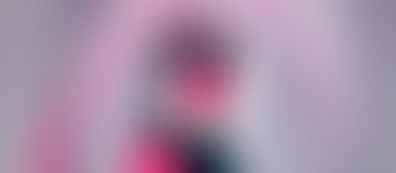 Futuristic portrait of a woman in a mesh hood and black visor, lit pink against a gray background.