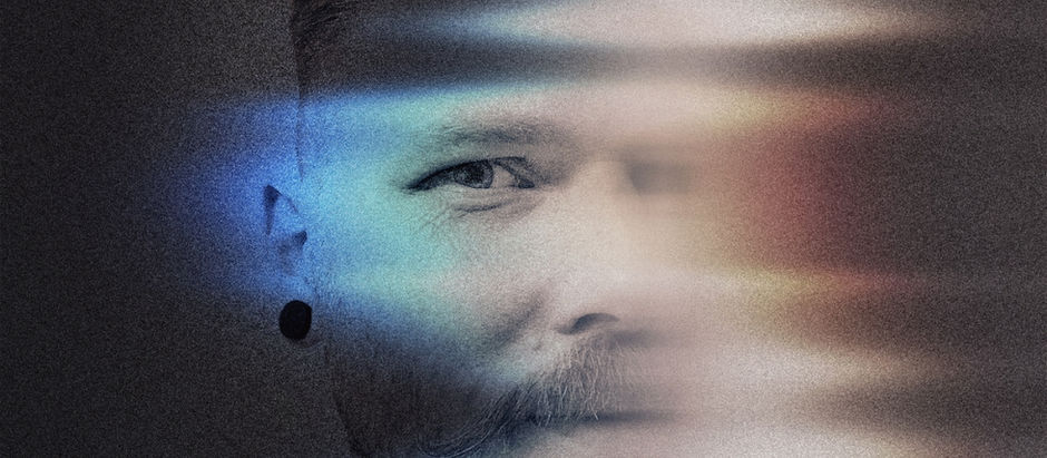 Abstract portrait of a person with a mustache, blurred light streaks in blue and red across face, dark background, moody atmosphere.