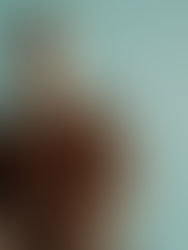 Man in brown shirt sits calmly against a teal background, conveying a relaxed mood. No visible text or patterns.