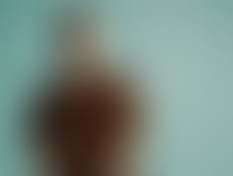 Man in brown shirt sits calmly against a teal background, conveying a relaxed mood. No visible text or patterns.